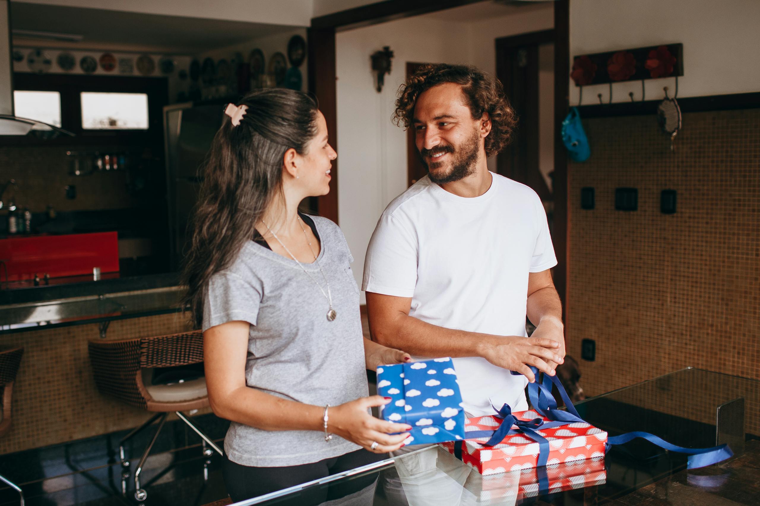 A couple sharing a joyful moment exchanging gifts in a cozy modern kitchen setting, fostering love and connection.