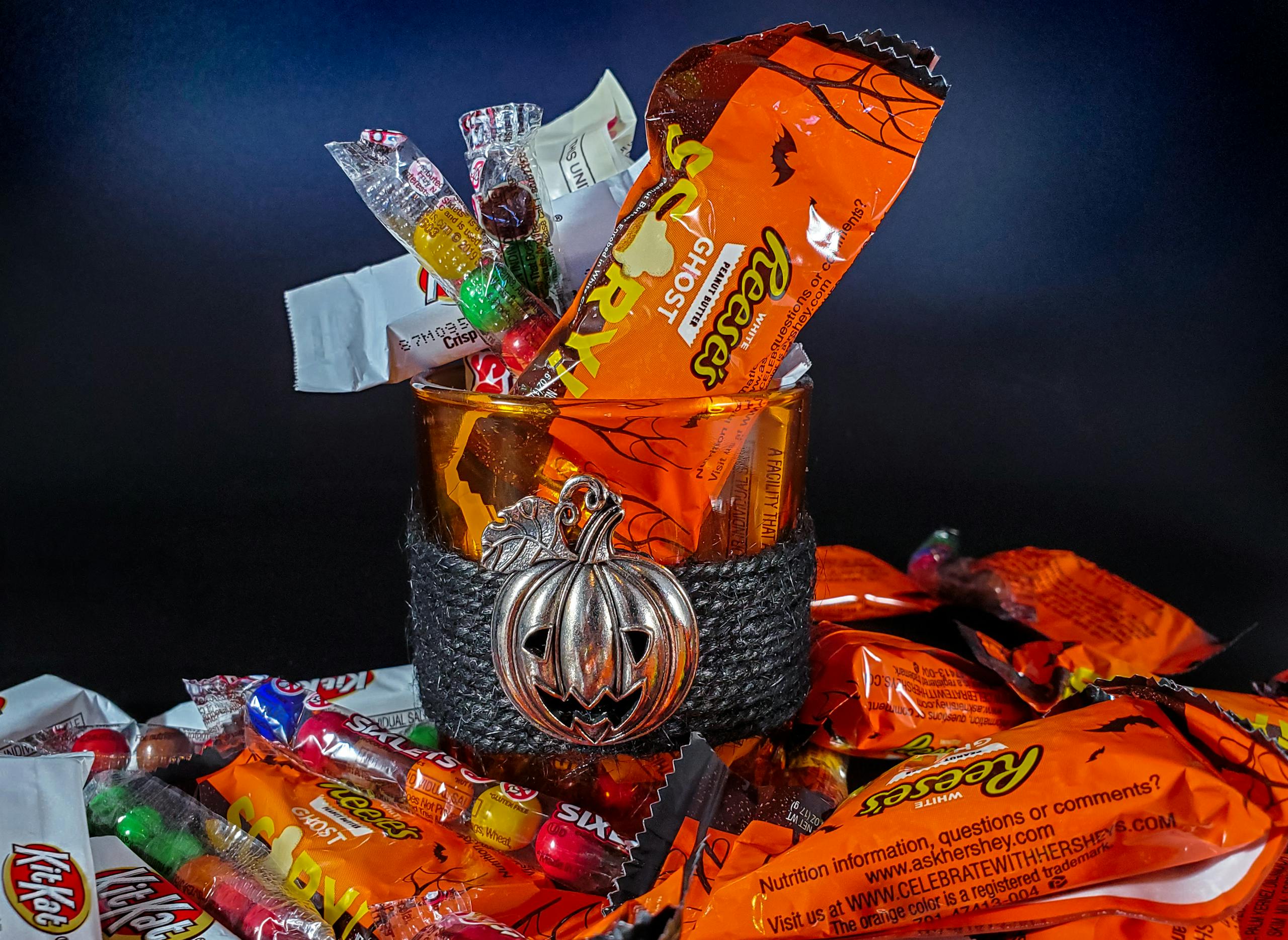 A vibrant collection of assorted Halloween candies in a glass bowl with a pumpkin decoration.