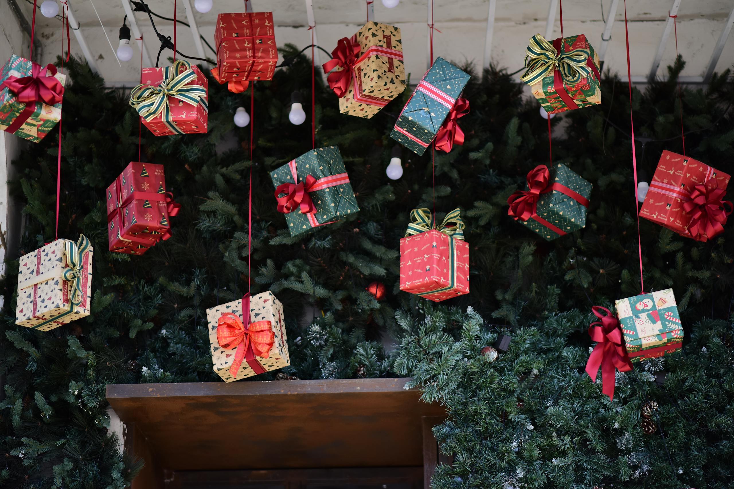 Colorful Christmas gift boxes with bows hanging in a festive setting.